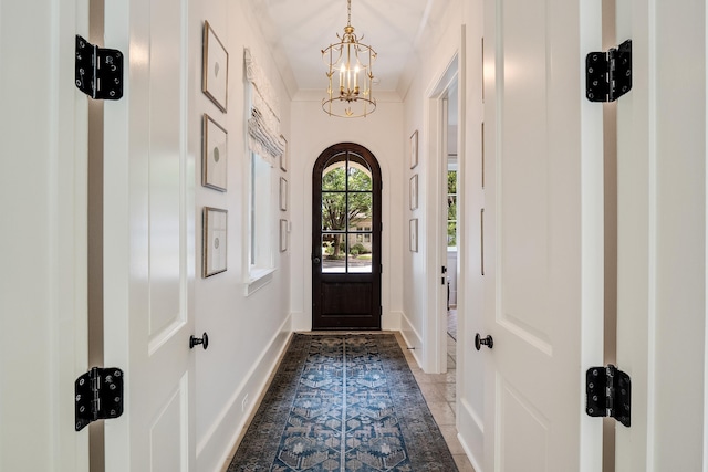 doorway featuring baseboards and an inviting chandelier