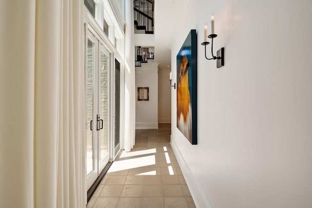 hallway with a wealth of natural light, light tile patterned floors, and baseboards