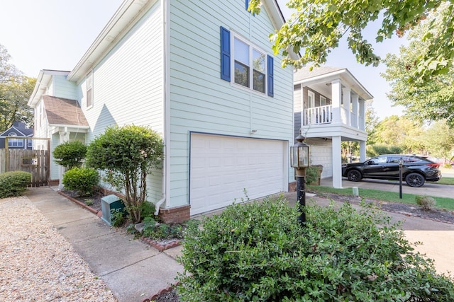 view of side of home with fence, aphalt driveway, and an attached garage