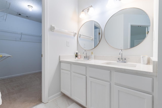 full bathroom with double vanity, a sink, a spacious closet, and visible vents