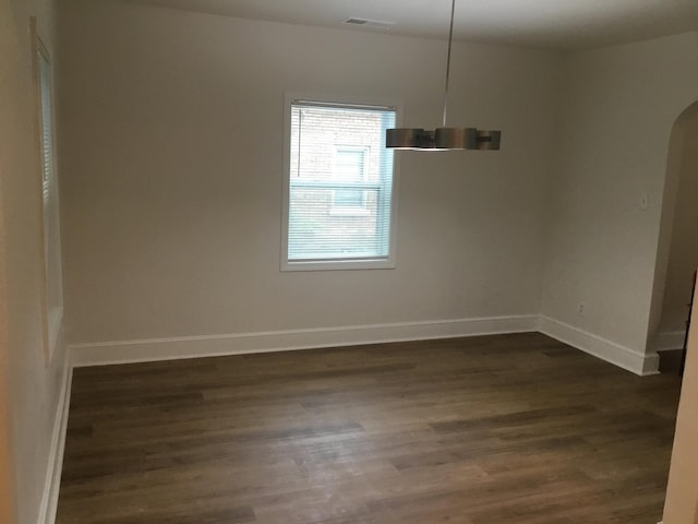 interior space featuring dark wood-style flooring, visible vents, baseboards, and arched walkways