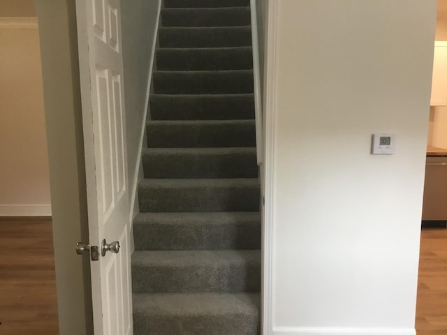 staircase featuring wood finished floors and baseboards