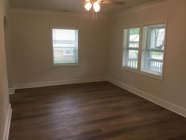 unfurnished room featuring dark wood-style floors, arched walkways, ceiling fan, and crown molding