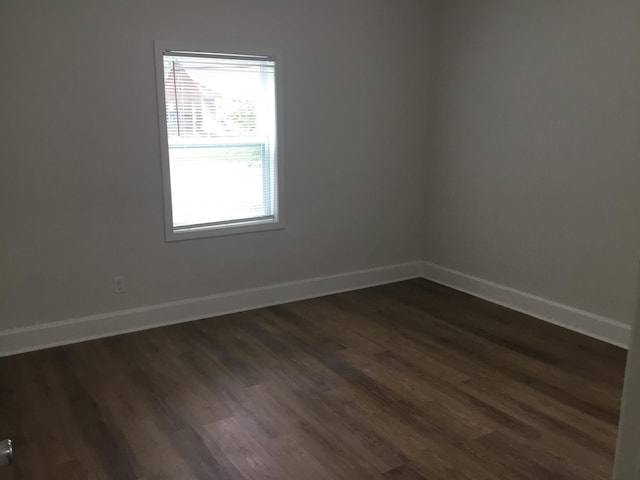 spare room featuring dark wood-style floors and baseboards