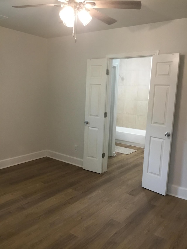 spare room featuring ceiling fan, dark wood-style floors, and baseboards