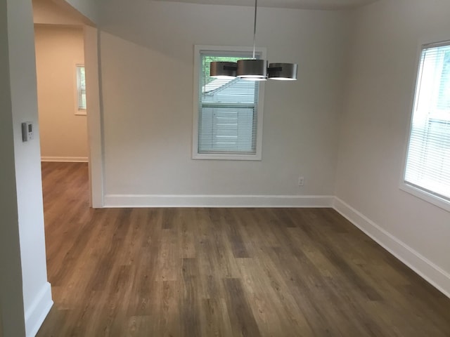 unfurnished dining area with dark wood-style floors and baseboards