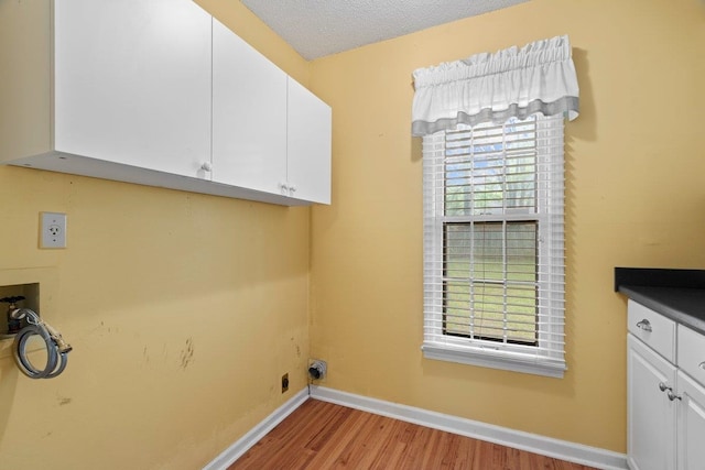 laundry room featuring light wood finished floors, cabinet space, washer hookup, baseboards, and a textured ceiling
