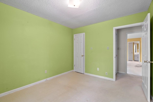 unfurnished bedroom featuring baseboards, light carpet, and a textured ceiling