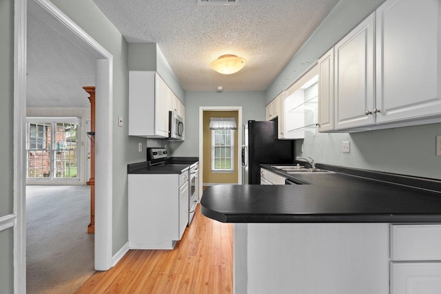 kitchen featuring range with electric cooktop, a textured ceiling, stainless steel microwave, dark countertops, and a wealth of natural light