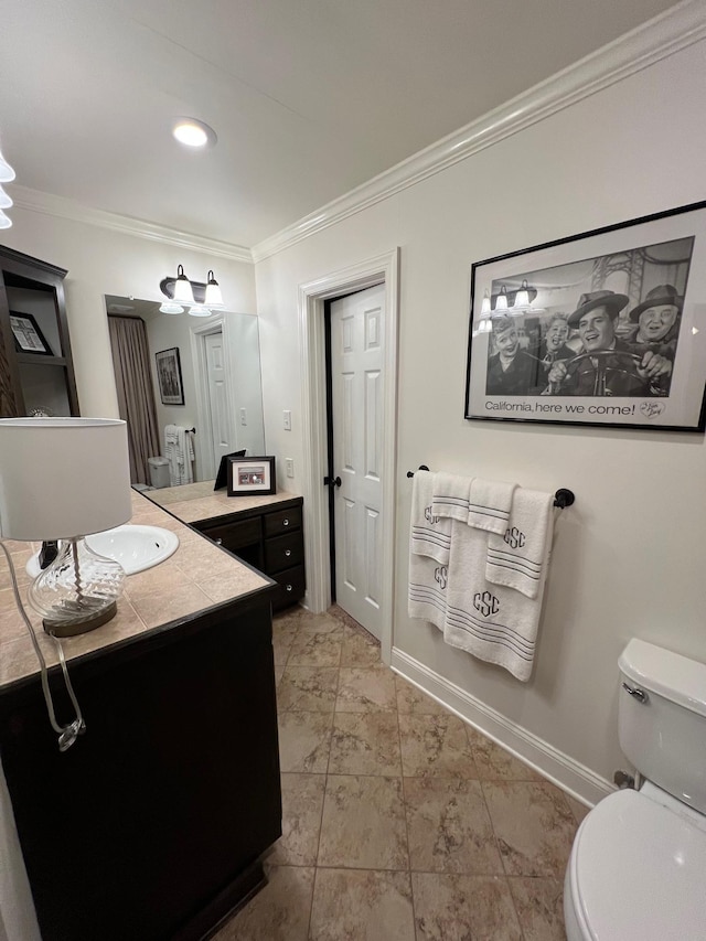 bathroom with crown molding, vanity, baseboards, and toilet