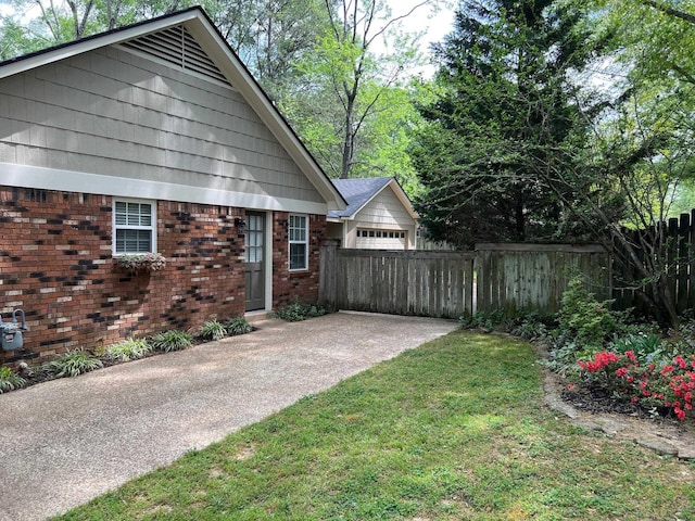 view of property exterior featuring a lawn, brick siding, fence, and a garage