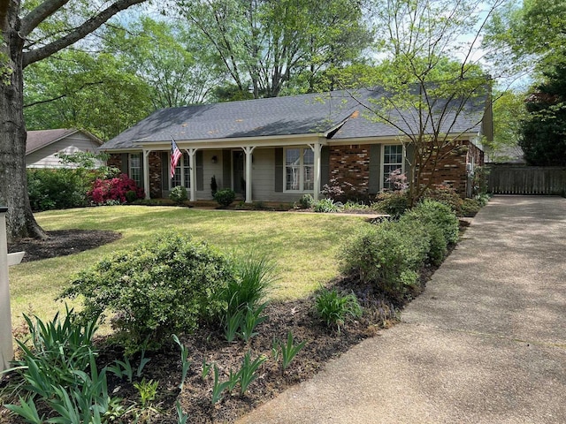 ranch-style home with covered porch, a shingled roof, and a front yard