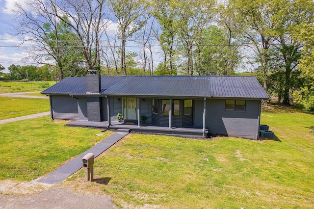 single story home featuring a porch, a chimney, metal roof, and a front yard