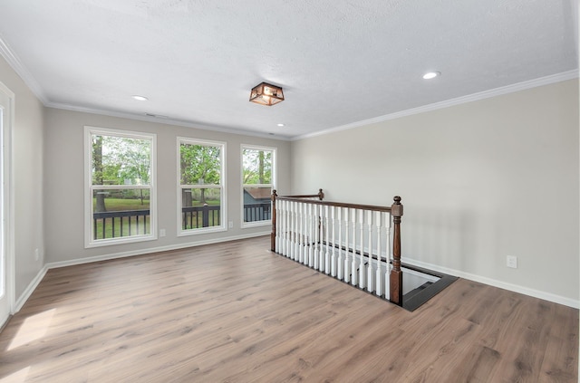 spare room with wood finished floors, crown molding, and baseboards