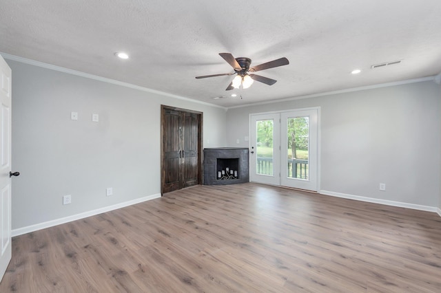 unfurnished living room featuring crown molding, a ceiling fan, visible vents, and a brick fireplace