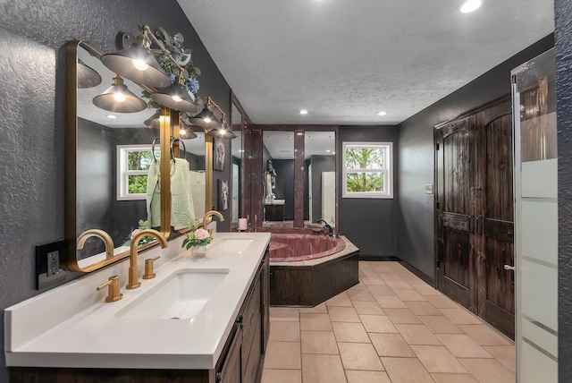 full bathroom featuring tile patterned floors, a textured ceiling, a bath, and a sink