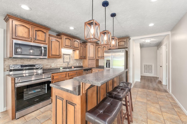 kitchen featuring decorative backsplash, appliances with stainless steel finishes, dark countertops, a sink, and baseboards