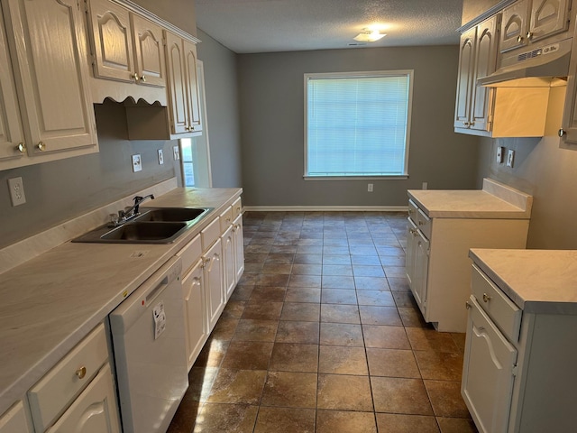 kitchen with a textured ceiling, a sink, light countertops, white dishwasher, and under cabinet range hood