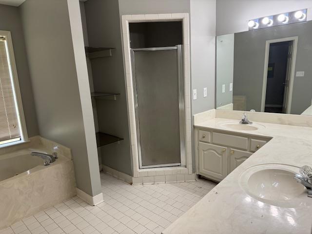 bathroom featuring a stall shower, tile patterned flooring, and a sink