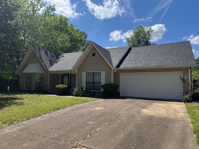 ranch-style house with a front yard, driveway, and an attached garage