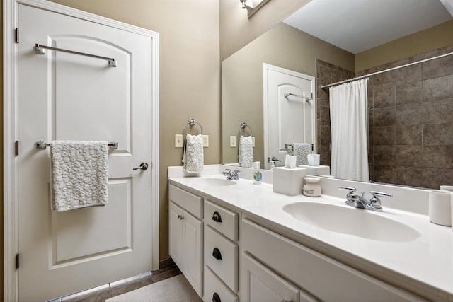 full bath with double vanity, a tile shower, tile patterned floors, and a sink
