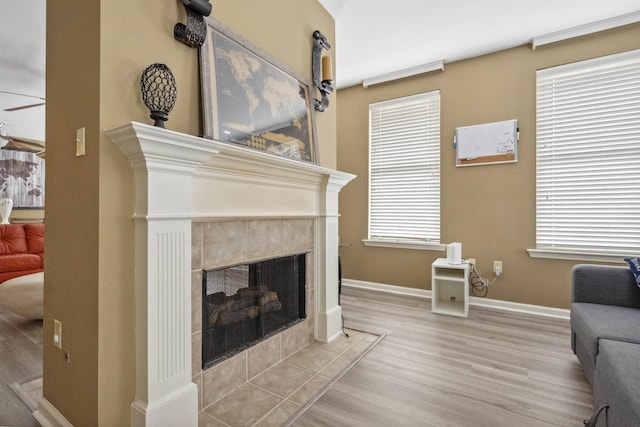 living area with a tile fireplace, wood finished floors, and baseboards