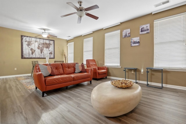 living area with a ceiling fan, visible vents, wood finished floors, and baseboards