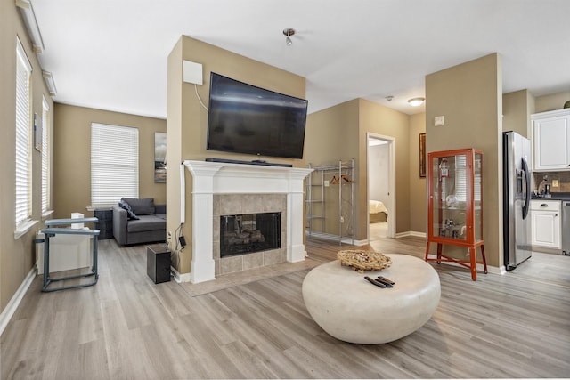 living area featuring a fireplace, baseboards, and light wood-type flooring