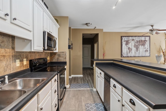 kitchen with stainless steel microwave, a sink, dark countertops, light wood finished floors, and range with electric stovetop