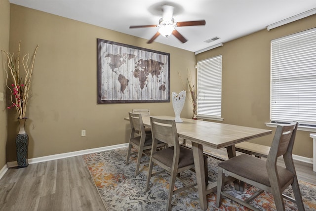 dining area featuring a ceiling fan, visible vents, wood finished floors, and baseboards