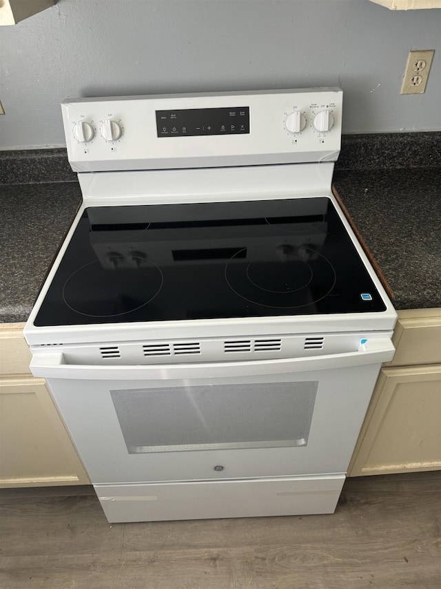 room details with dark countertops, wood finished floors, and white electric stove