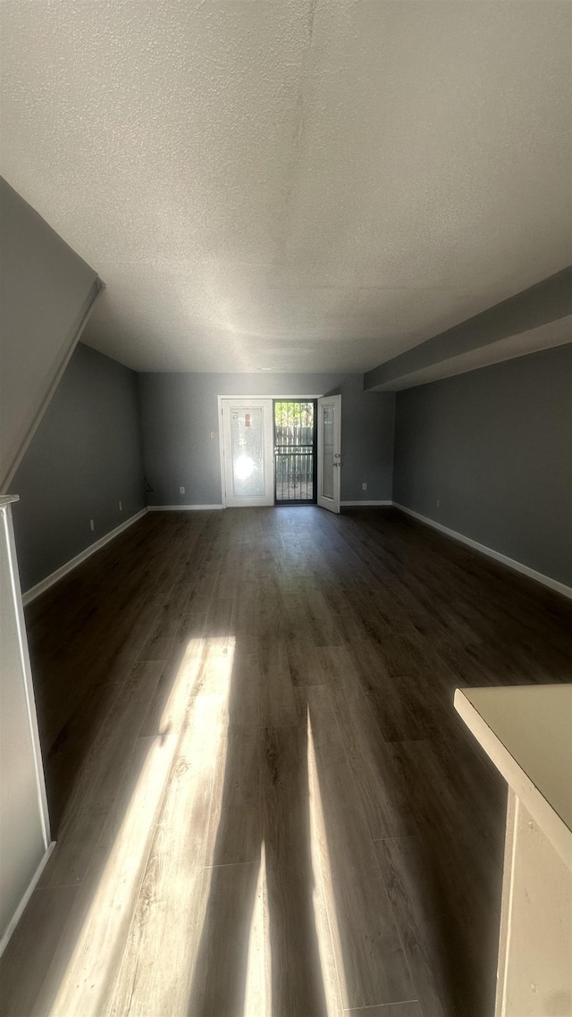 unfurnished living room featuring baseboards, a textured ceiling, and dark wood-type flooring