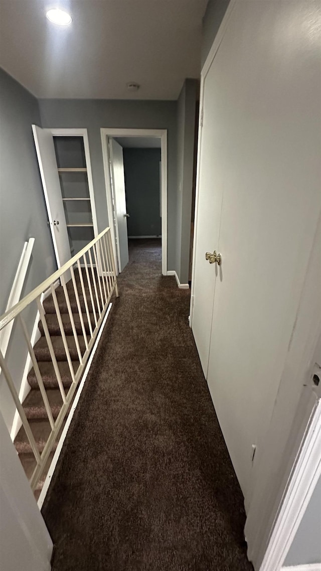 hallway featuring stairs, carpet floors, and baseboards