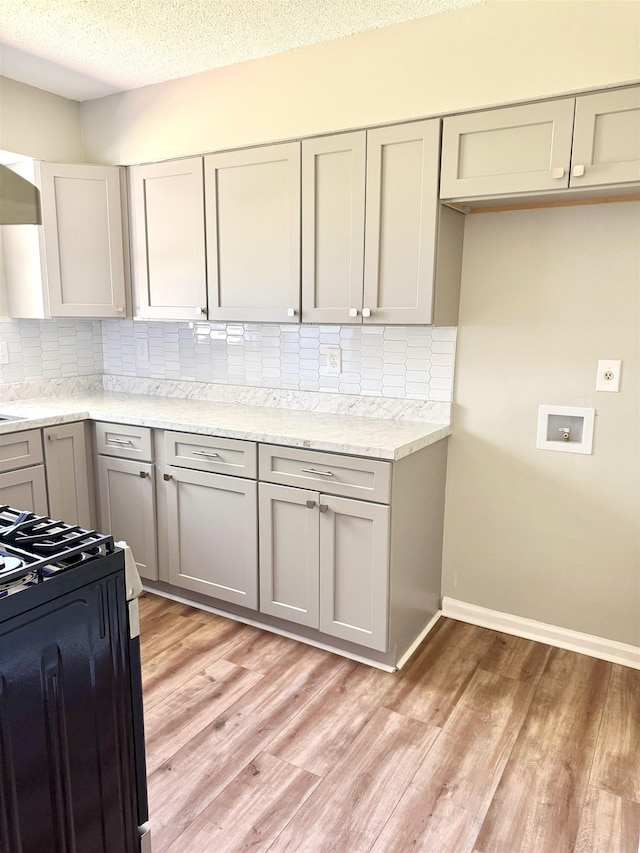 6330 Martinwest Dr, Millington, TN 38053 - kitchen featuring light wood finished floors, decorative backsplash, a textured ceiling, gray cabinetry, and black gas range oven