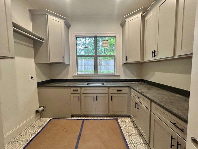 clothes washing area featuring baseboards and cabinet space