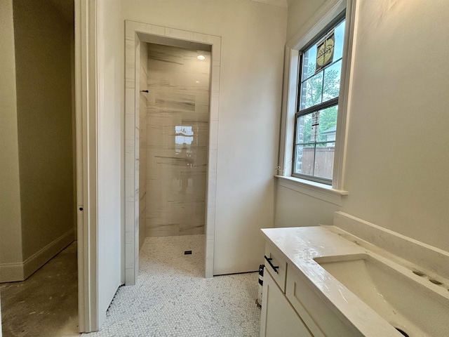 full bathroom featuring baseboards, tiled shower, vanity, and a healthy amount of sunlight