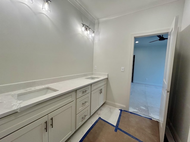 bathroom featuring marble finish floor, double vanity, and baseboards
