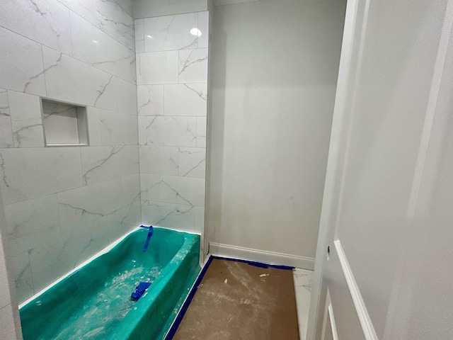 full bath featuring a tub and baseboards