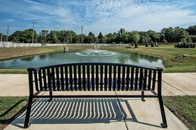 view of community featuring a lawn, a water view, and fence