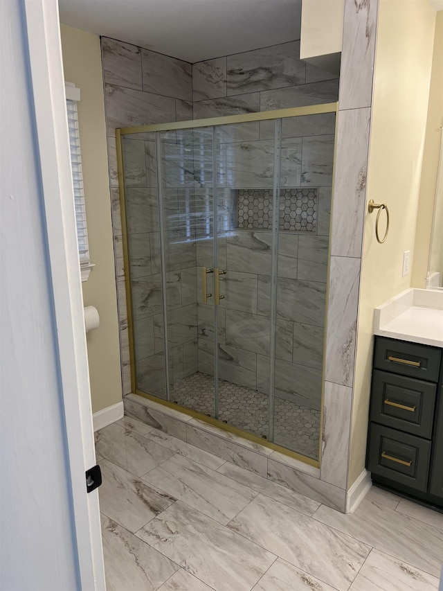 full bathroom with marble look tiles, baseboards, a stall shower, and vanity