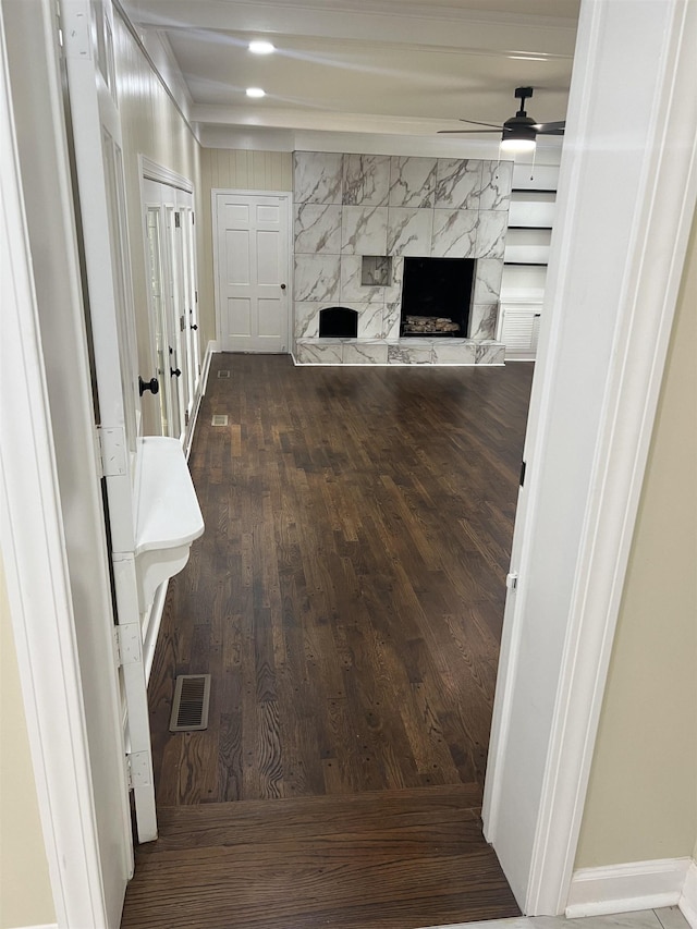 unfurnished living room featuring a ceiling fan, wood finished floors, a fireplace, and baseboards