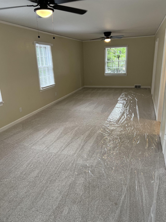 unfurnished room with a ceiling fan, baseboards, ornamental molding, and carpet flooring