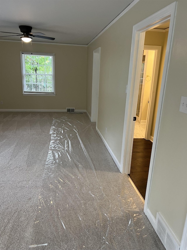 unfurnished room with ornamental molding, a ceiling fan, baseboards, and carpet flooring