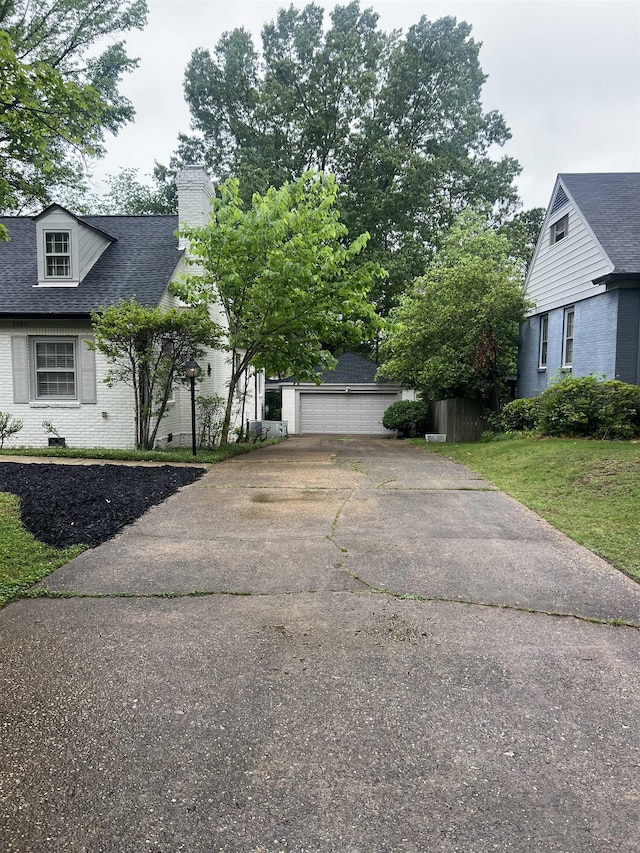 view of property exterior with a chimney, a shingled roof, brick siding, and a garage