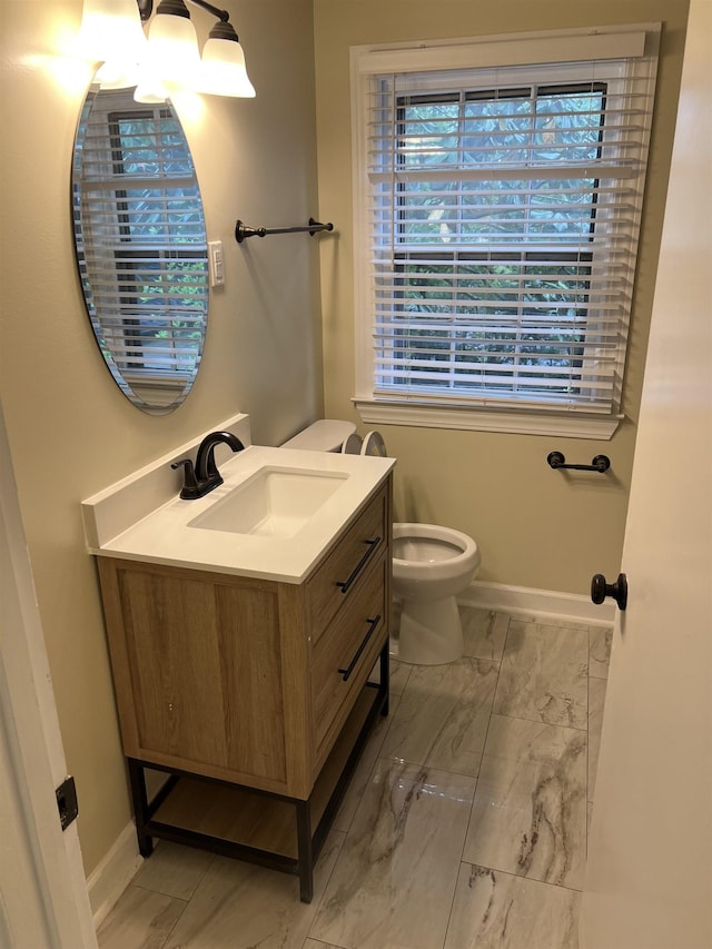 bathroom with marble look tiles, baseboards, vanity, and toilet