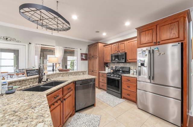 kitchen with brown cabinets, crown molding, a sink, stainless steel appliances, and light stone countertops