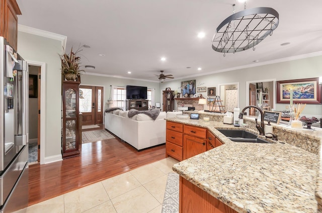 kitchen with light stone counters, ceiling fan, crown molding, and a sink