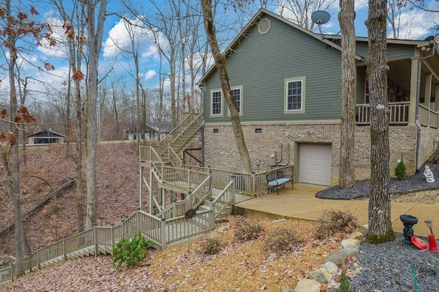 back of house featuring stairs, a garage, and brick siding