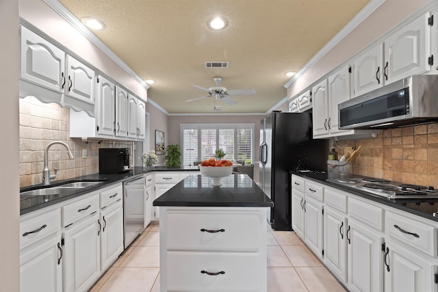 kitchen with a sink, visible vents, a kitchen island, ornamental molding, and appliances with stainless steel finishes