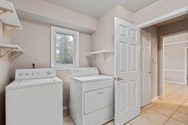 laundry room featuring baseboards, light tile patterned flooring, laundry area, and independent washer and dryer